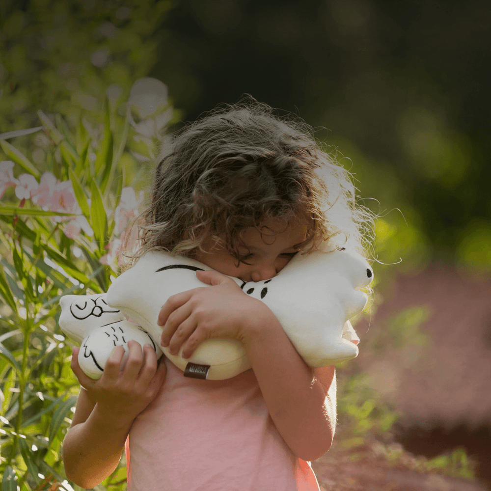 bambina felice che abbraccia un cuscino a forma di scoiattolo